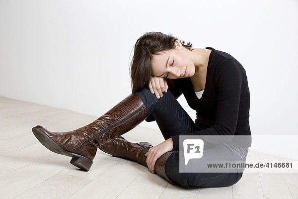 Verzweifelte junge Frau sitzt auf dem Boden