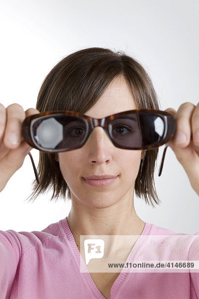 Junge Frau schaut durch Sonnenbrille