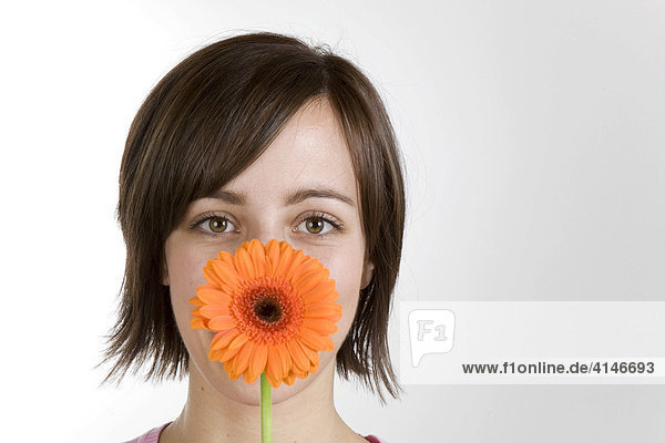 Junge Frau mit Blume vor dem Gesicht