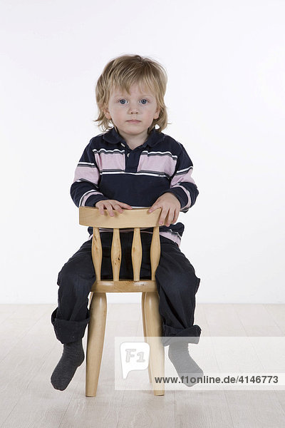 Kleiner Junge sitzt auf einem Stuhl