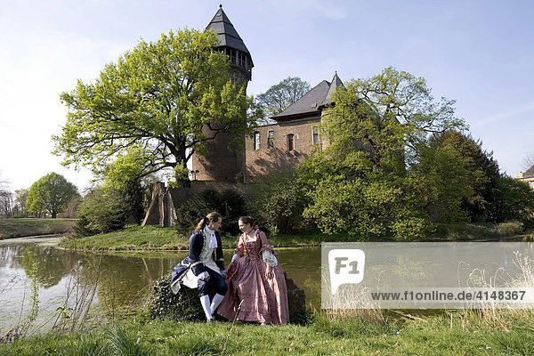 Junges Pärchen in Rokoko-Kleidung posiert vor der Wasserburg Linn  Krefeld  NRW  Deutschland