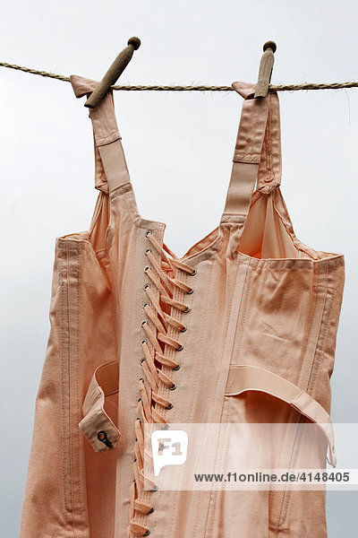 Old fashioned bodice  hanging on a clothesline  fixed with wooden pegs