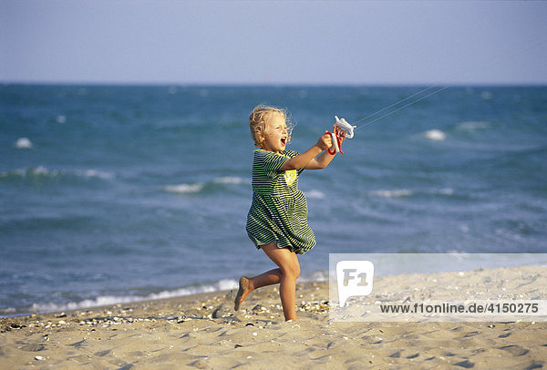 Fünfjährige am Strand mit Drachenschnüren