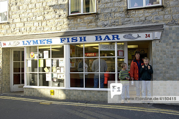 Mutter mit zwei Kindern kauft Fish and Chips in Lyme Regis Dorset England