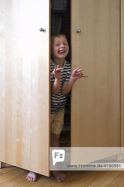 Kleiner Junge versteckt sich im Schrank und spielt Monster