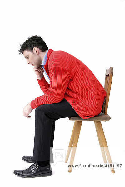Mann in roter Jacke sitzt auf altem Holzstuhl