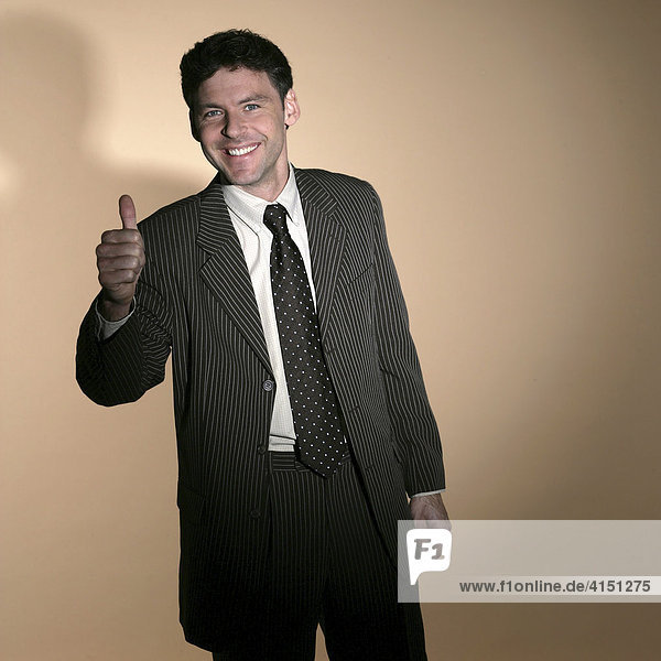 Man wearing suit smiling and giving a thumbs up