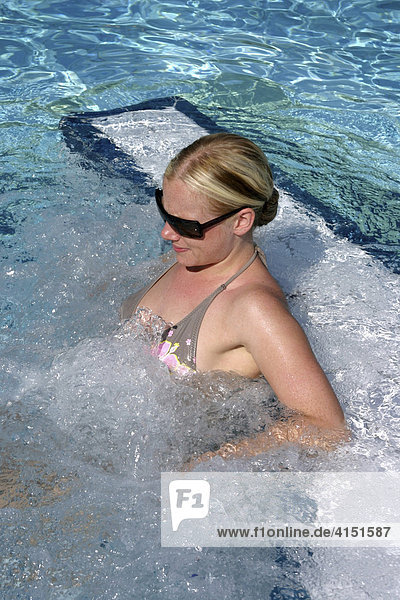 Junge Frau lehnt am Beckenrand eines Schwimmbades