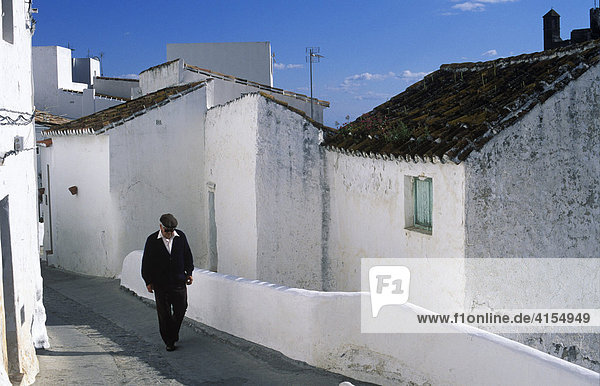 Man walking down a street in the whitewashed town of Casares  Málaga Province  Andalusia  Spain