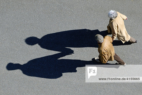 Senior couple walking hand-in-hand  bird's eye view with shadow