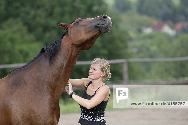 Junge Frau krault ihr Pferd am Hals
