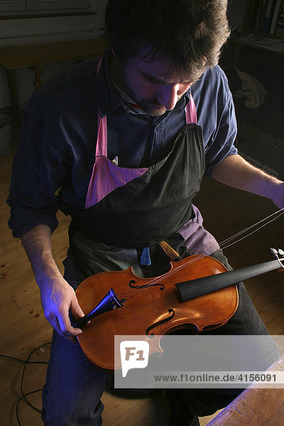 Geigenbauer beim Bespannen einer Geige