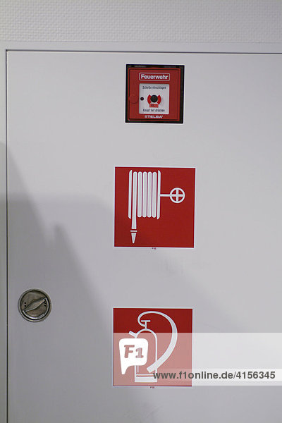 Drei rote Hinweisschilder für Feuermelder auf weisser Tür