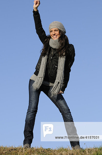 Brunette woman wearing woolen hat and scarf and leather jacket  dancing