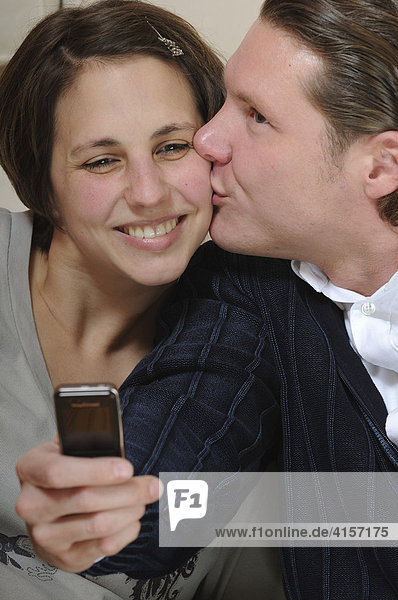 Mann küsst seine Freundin und macht ein Foto mit dem Handy