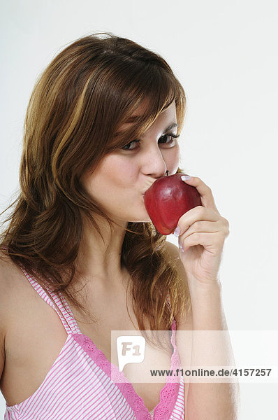 Pretty young brunette woman eating a red apple