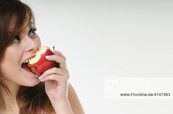 Hübsche junge braunhaarige Frau isst einen roten Apfel