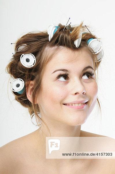 Pretty young brunette woman with curlers in her hair