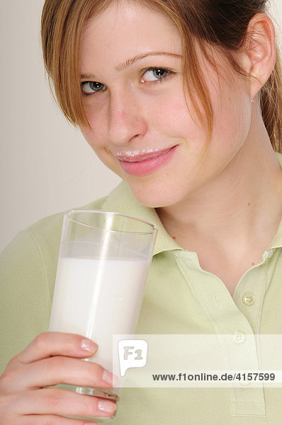 Junge  langhaarige Frau mit grünem Polo-Hemd trinkt Milch