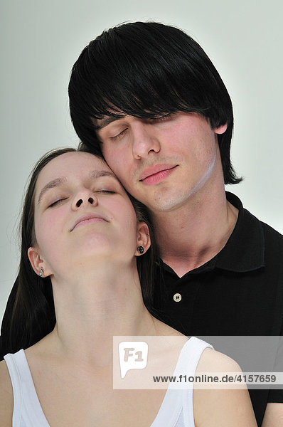 Junges  schwarzhaariges Paar umarmt sich mit geschlossenen Augen  Portrait