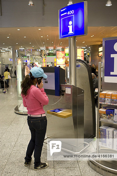 Junge Frau telefoniert im Terminal 1 an einem Informationsschalter  Flughafen Frankfurt  Hessen  Deutschland