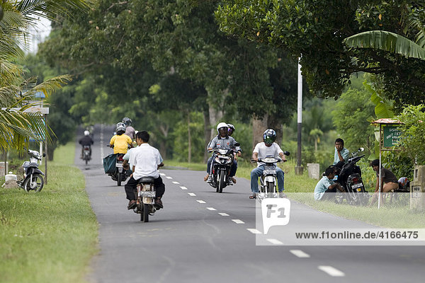 People driving mopeds along a highway going to Matram  capital of Lombok Island  Lesser Sunda Islands  Indonesia