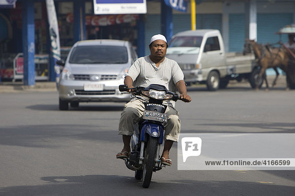 Muslim man riding a moped through the streets of the capital  Mataram  Lombok Island  Lesser Sunda Islands  Indonesia