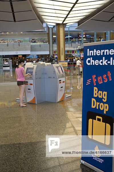 Junge Frau am Internet Check-In in der Abflughalle am Changi Airport  Flughafen  Singapur  Südostasien  Asia