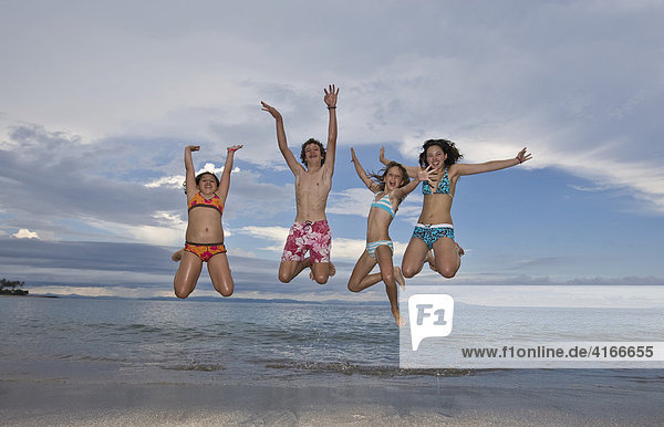 Four children jumping with joy on the beach  Lombok Island  Lesser Sunda Islands  Indonesia  Asia