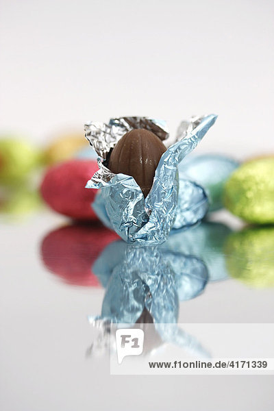 Schokoladen-Eier auf Spiegel  ein geöffnetes Schokoladen-Ei im Vordergrund  Ostern