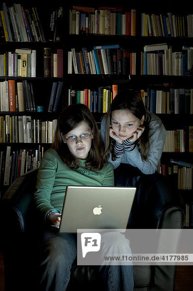 10jährige Mädchen an Computer vor Bücherwand