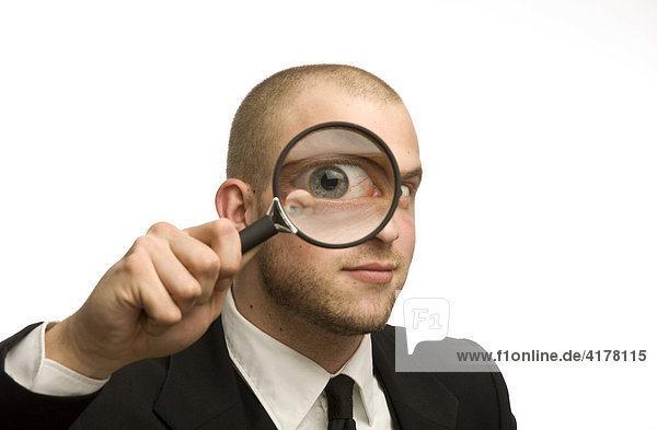Young man holding magnifying glass in front of his face