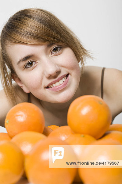 Many oranges in front of a laughing young woman
