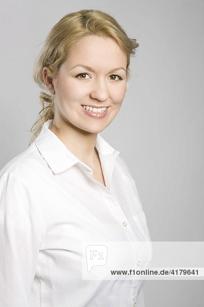 Portrait einer jungen blonden Frau in weißer Bluse  lachend