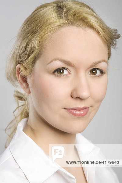 Portrait of a young blonde woman wearing a white blouse  smiling