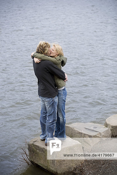 Paar küßt und umarmt sich am Wasser stehend
