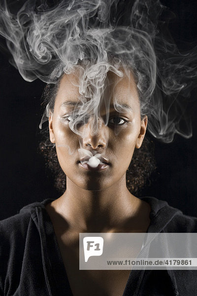 Young  dark-skinned woman smoking a cigarette  cigarette smoke