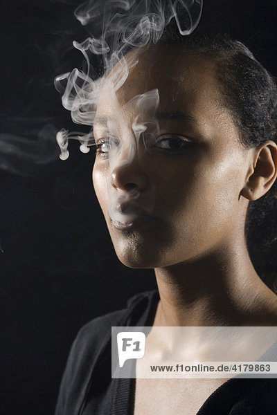 Young  dark-skinned woman smoking a cigarette  cigarette smoke