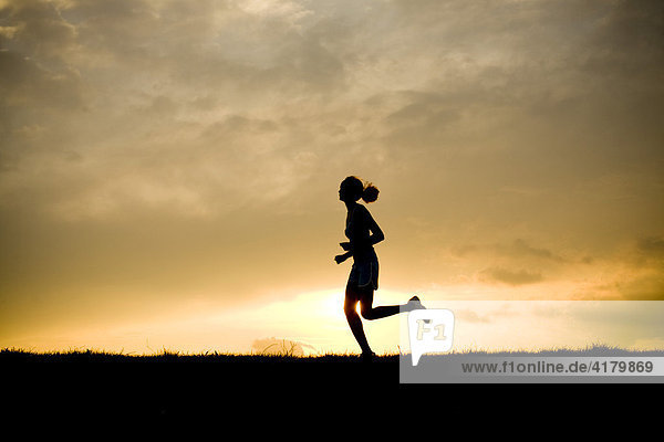 Silhouette of a woman jogging at sunset