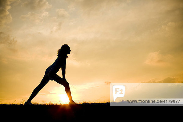Silhouette of a woman stretching at sunset