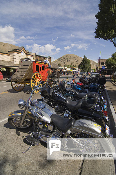Harley Davidson Motorräder stehen geparkt in Jackson hinten fährt eine Postkutsche Wyoming Vereinigte Staaten von Amerika