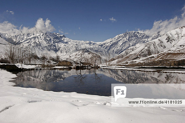 Schneebedeckte Berge spiegeln sich im Wasser eines kleinen Sees beim Bergdorf Jharkot  Nepal  Asien