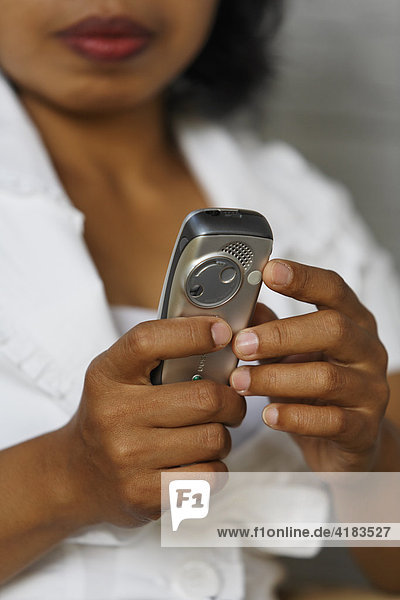 Frau aus Asien hält Mobiltelefon in der Hand