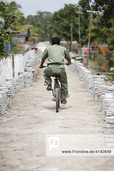 Lehrer auf Fahrrad im Dorf Tanjung Harapan  Zentral-Kalimantan  Borneo  Indonesien