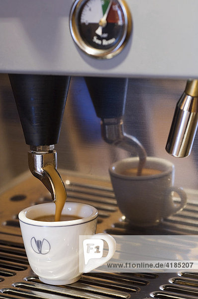 Mit einer Espressomaschine wird eine Tasse Kaffee zubereitet  gefüllt.
