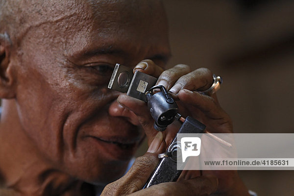 Mann prüft Schliff von Diamant  Diamantenschleiferei  Cempaka  Süd-Kalimantan  Borneo  Indonesien  Asien