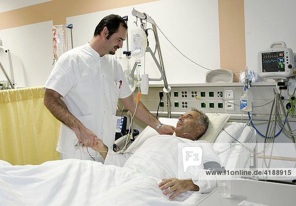 A male nurse supplies a patient in a waking up area in a Munich Hospital after an operation at his knee.