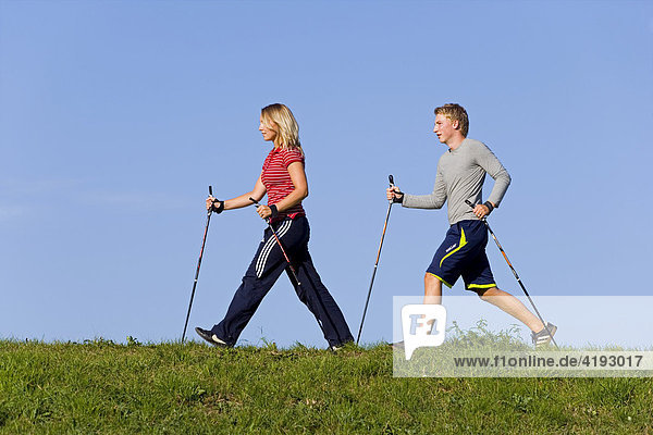 A young woman and a young man doing nordic walking