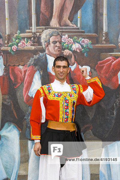 Man wearing traditional costume standing in front of a wall mural in the mountain village of Fonni  Sardinia  Italy