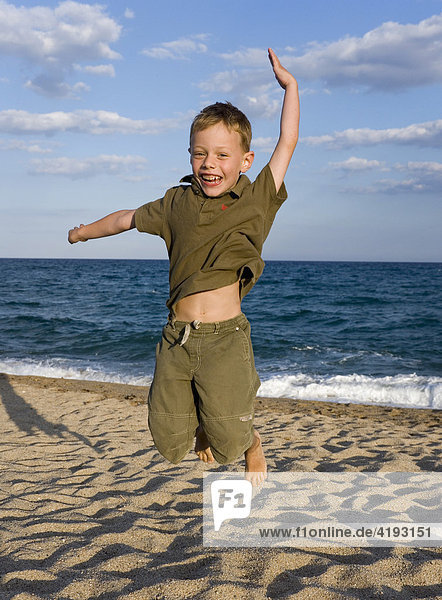 Five-year-old boy jumping for joy at a beach
